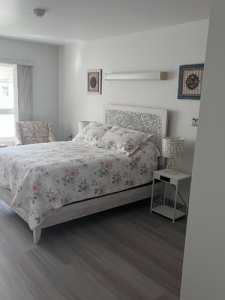 Bright guest bedroom suite with a bed, side tables, and window with armchair.
